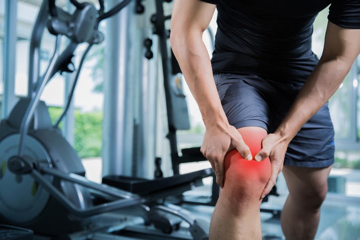 Man holding knee with at gym